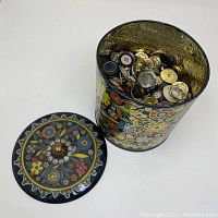 Open floral decorated round cookie tin showing assorted buttons inside
