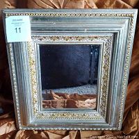 Front view of square bevelled mirror showing the silver frame with gold floral detailing.