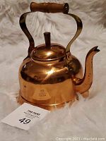 Front and side view of the copper pot showing the wooden handle, lid and spout.