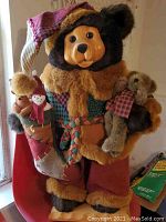 Full view of Dan Dee Collectors Choice bear, showing the plush body in colorful holiday fabric clothing holding two teddy bears and wearing a Santa style hat.