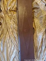 Closed brown textured hard rifle case with embossed diamond pattern and a raised emblem of Ducks Unlimited flying duck logo on the case surface.