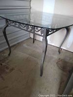 Side angle showing the rectangular clear glass top and metal frame with curved legs.