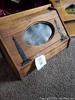 Full view of the mid century wooden bread box showing the hinged lid with oval metal panel.