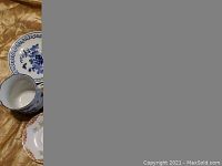 Partial view of small hand painted dish with blue floral pattern and various tea cups and saucers.