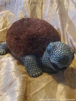 Full view of the turtle-shaped boot cleaner and door stop showing the bristle shell and sculpted head and limbs.