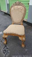 Front view of vintage accent chair showing upholstered seat and backrest with carved wooden frame and claw feet.