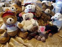 Lot of seven vintage teddy bears and one small plush seal on a bedspread.