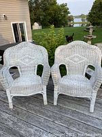 Pair of white wicker chairs on an outdoor wooden deck showing overall condition and style