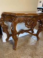 Full side view of console table showing ornate carved legs and apron