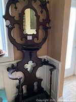 Full front view of ornate wooden hall stand showing mirror, shelf, side supports and base tray