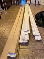 Photo showing the full length of white pre-primed crown moulding pieces laid on floor alongside packaging boxes.