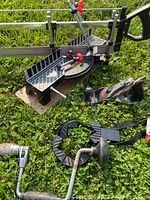 Full view of all tools on grass including mitre saw, hand plane, hand drills, and clamp under natural light