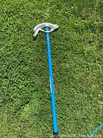 Full length view of the blue handled pipe bender lying on grass