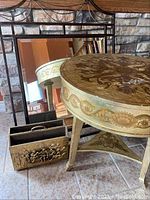 Photo showing large rectangular mirror with metal frame, round decorative table, and metal magazine holder grouped together.