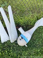 Photo showing three white tapered wind turbine blades laid on grass next to a white plastic turbine hub with blue band.