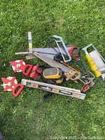 View of the full lot on grass showing saws, clamps, spirit level, knee pad, and measuring tapes.