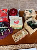 Photo showing all fishing reels and the lure with original boxes on a wooden table surface.