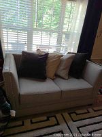 Full front view of loveseat with four throw pillows under window