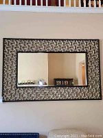 Full view of rectangular mirror showing decorative silver geometric frame and black inner border