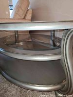 Side view showing curved metallic frame with glass shelf below