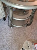 Side view of the end table showing wooden frame, curved legs, and circular glass shelf