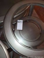 Top-down photo showing clear glass top inset into silver metal frame with label attached.