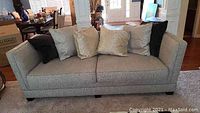Front view of full sofa with light grey upholstery and included pillows