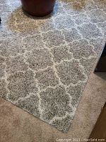 Corner view of rug on carpeted floor showing grey and white pattern