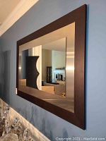 Straight-on view of mirror hung on blue wall above sideboard with glass decanters