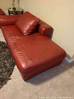 Left front view of red leather chaise lounge on carpet