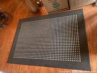 Full view of the brown rug with white square pattern on wooden floor.