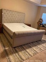 Full view of upholstered king bed frame with mattress atop adjustable black metal base in bedroom.