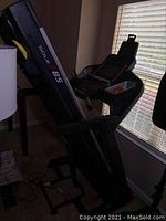 Folded treadmill frame and running deck upright against window