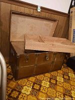 Open trunk showing interior lined with diamond pattern fabric and removable tray.