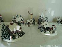 Front view showing five different Thomas Kinkade Christmas village pieces arranged on table