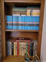 Shelves of vintage books including a complete or near-complete set of The Hardy Boys series with blue dust jackets and other assorted vintage books, along with metal book ends.