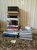 Stack of assorted hardcover and softcover military books and periodicals arranged on the floor.