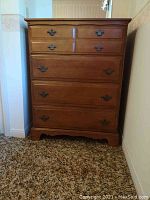 Front view of maple 4-drawer dresser against a wall on carpeted floor.