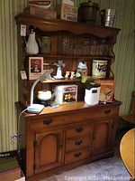Full view of the wooden buffet with various kitchen items on top (not included). Shows the medium-tone wood finish and traditional design.
