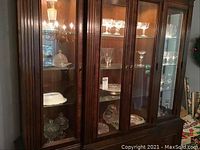 Photo of glassware and ceramic items inside china cabinet including bowls, platters, glasses, candle holders