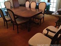 Full dining room view showing the set of eight dining chairs arranged around a wooden dining table. Two armchairs are visible along with six armless chairs.