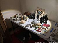 Wide shot of table displaying assorted items including metal and wooden model cars, miniature Coke bottles from various locations, Boy Scout memorabilia, and other small collectibles.