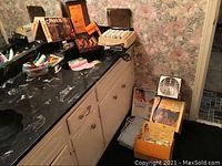 Countertop with various hair care items including curlers, boxed hair dryers, heating pad, and Norelco sun lamp.