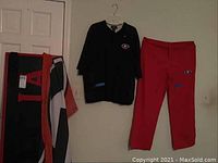 Black shirt and red pants hanging on wall showing UGA logos and Nike swooshes