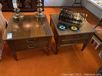 Two wooden square end tables side by side with drawers closed, showing medium finish and some surface scratches.