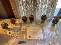 Five porcelain eggs displayed on table with certificates of authenticity