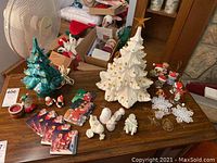 Photo showing full lot with ceramic Christmas trees, ceramic figurines, coasters, and ornaments on table
