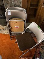 Four folded Samsonite Monarch folding chairs stacked, visible metal frames and wood-tone seats with scratches.