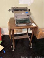 Full view of Royal manual typewriter on the folding typing table showing the table legs and wheels.