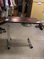 Full view of the rolling bed table cart with wooden top and metal frame showing its structure.